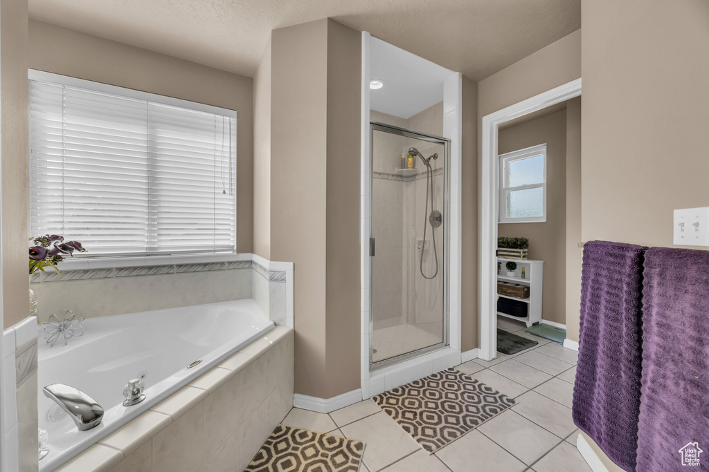 Bathroom with a garden tub, a stall shower, tile patterned flooring, and baseboards