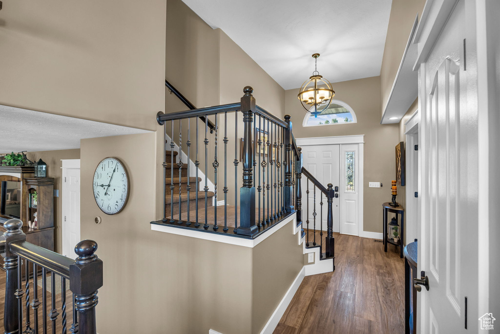 Foyer with baseboards, a chandelier, wood finished floors, a towering ceiling, and stairway