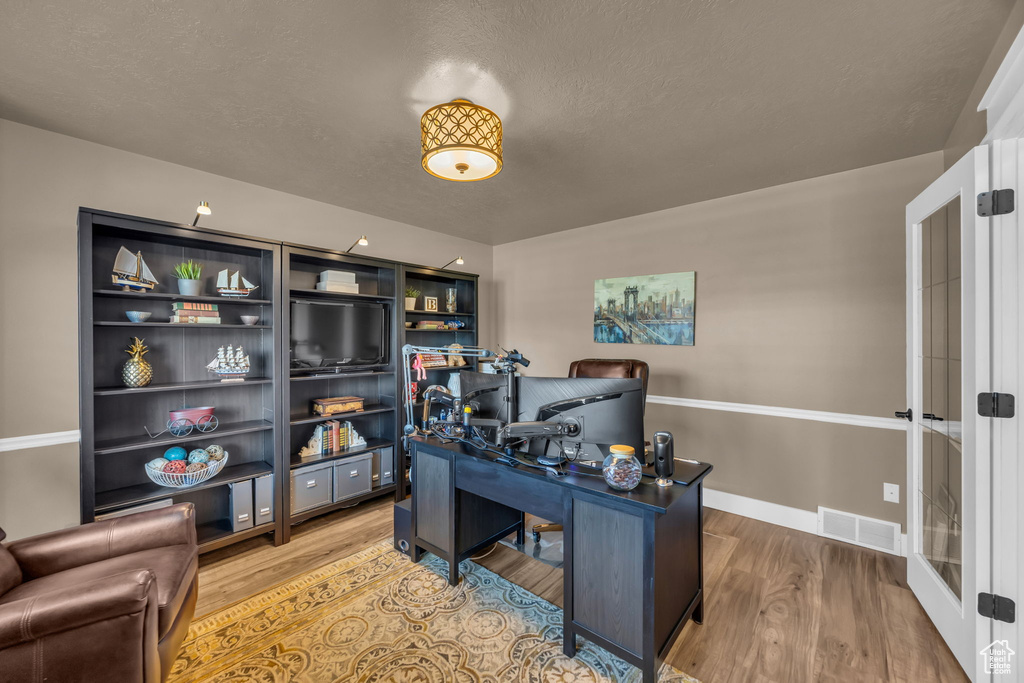 Office area with wood finished floors, french doors, a textured ceiling, and baseboards
