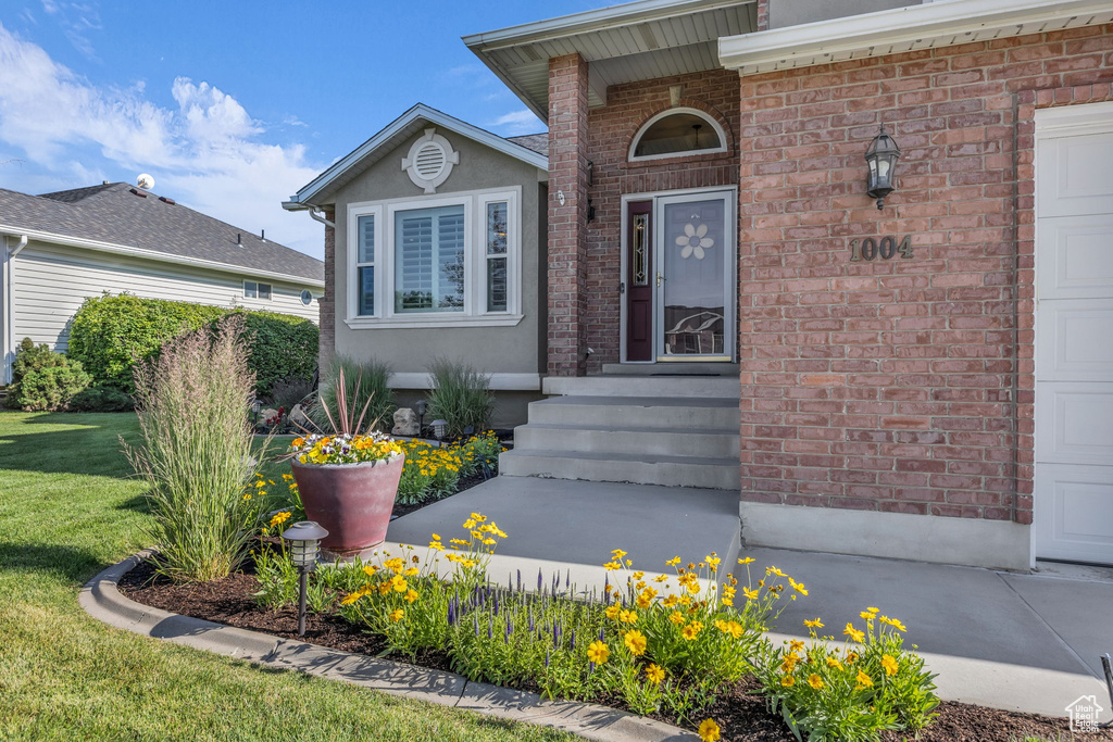 Entrance to property featuring brick siding, stucco siding, and a yard