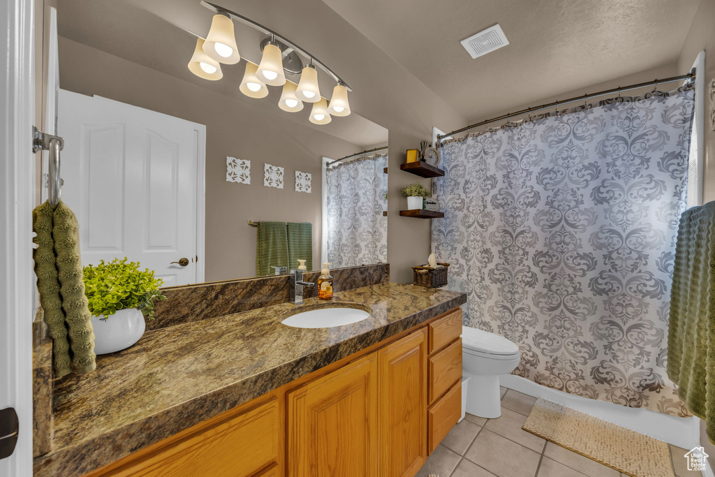 Full bathroom featuring tile patterned floors, toilet, vanity, and curtained shower