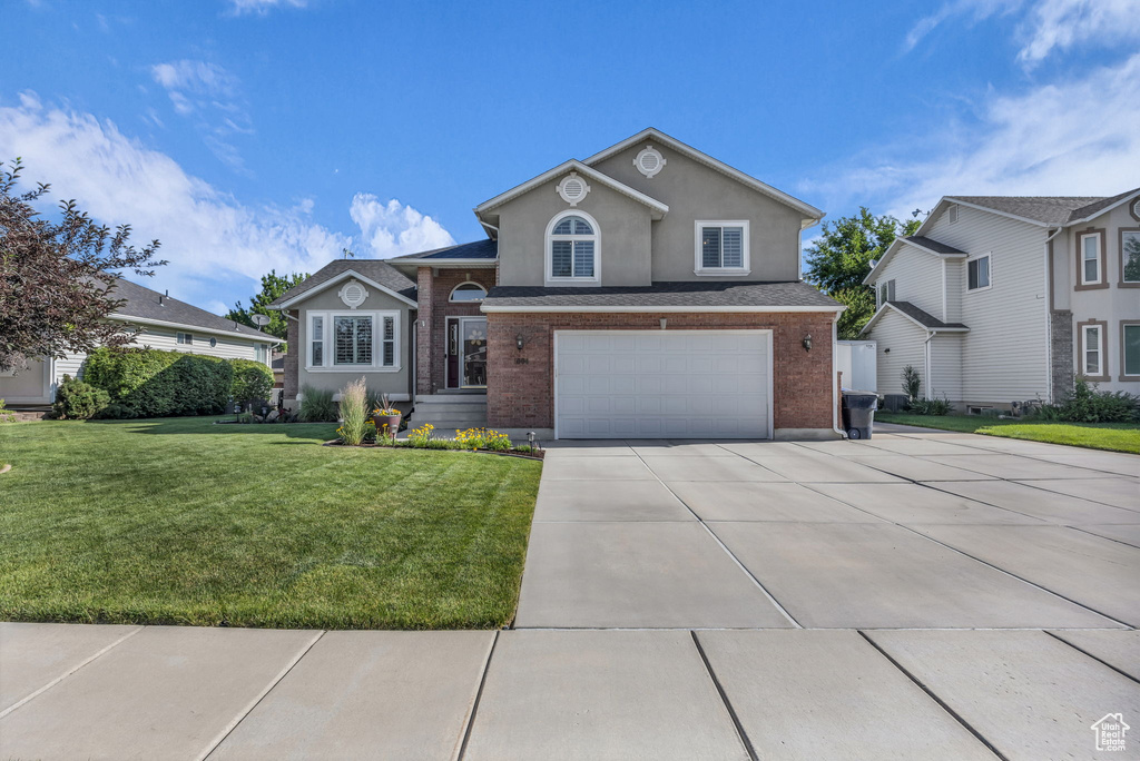 View of front of property with an attached garage, concrete driveway, brick siding, and stucco siding