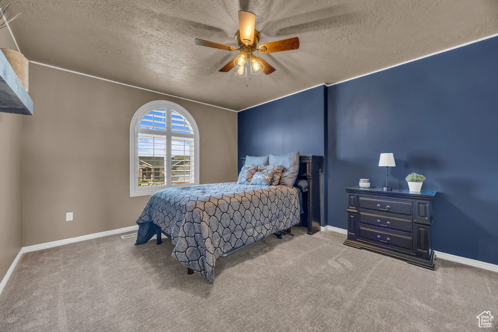 Carpeted bedroom with a textured ceiling, baseboards, and ceiling fan