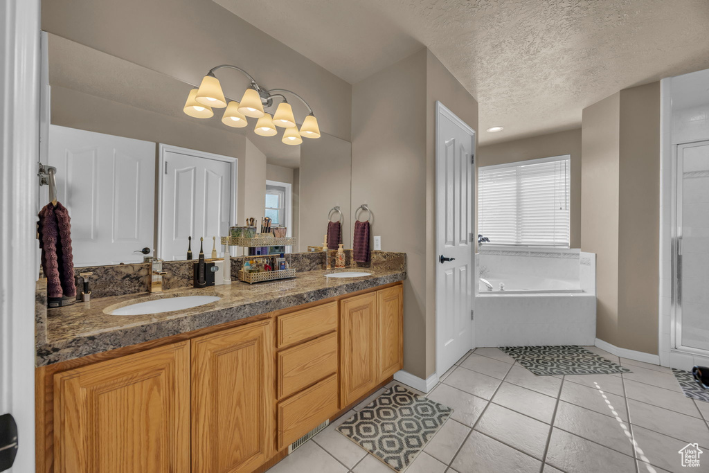 Bathroom featuring double vanity, baseboards, a garden tub, tile patterned floors, and a textured ceiling