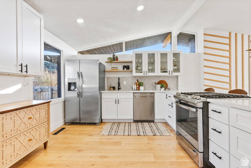 Kitchen featuring appliances with stainless steel finishes, light wood finished floors, decorative backsplash, white cabinets, and recessed lighting