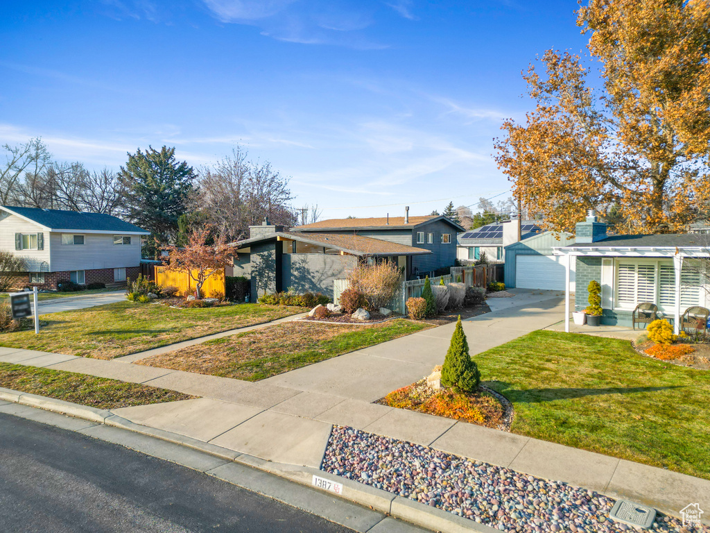 View of front of house with a residential view, a detached garage, and driveway
