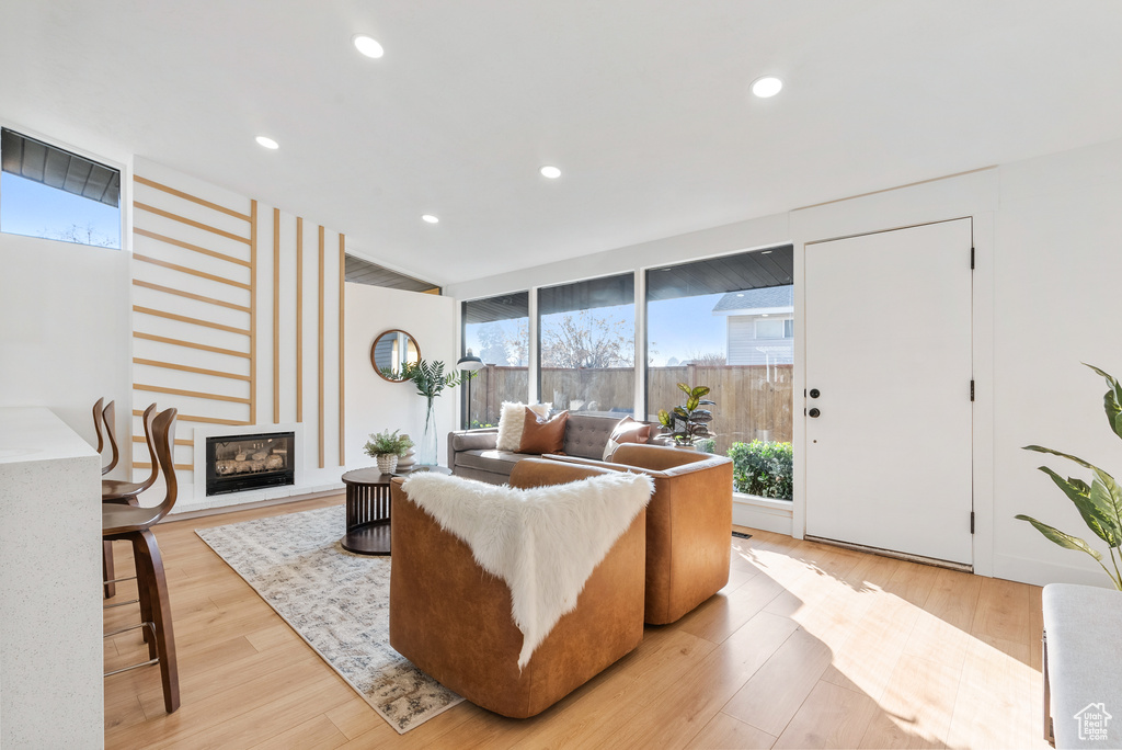 Living room featuring plenty of natural light, a fireplace, light wood finished floors, and recessed lighting