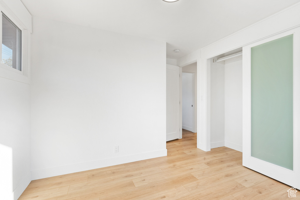 Unfurnished bedroom with light wood-style floors, baseboards, and a closet