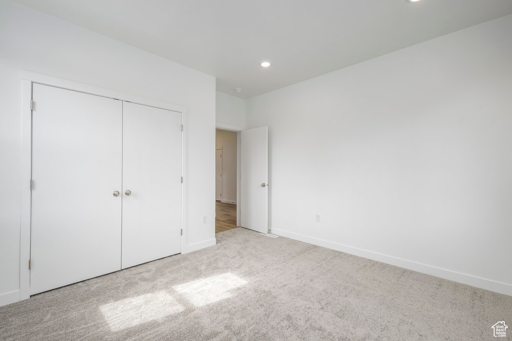 Unfurnished bedroom with carpet floors, recessed lighting, baseboards, and a closet