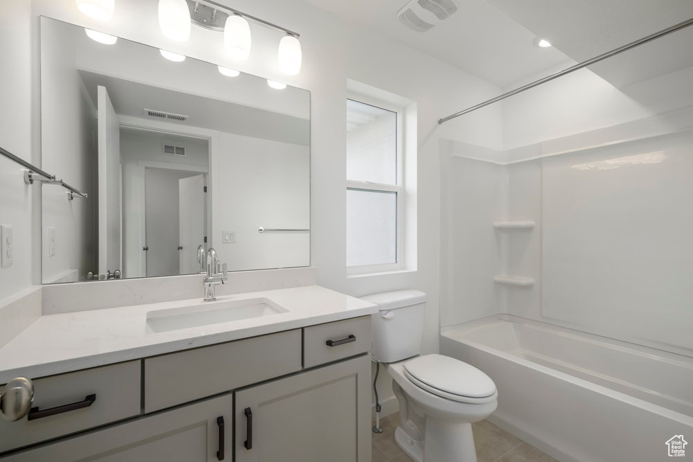 Bathroom with vanity, toilet, tub / shower combination, and tile patterned flooring