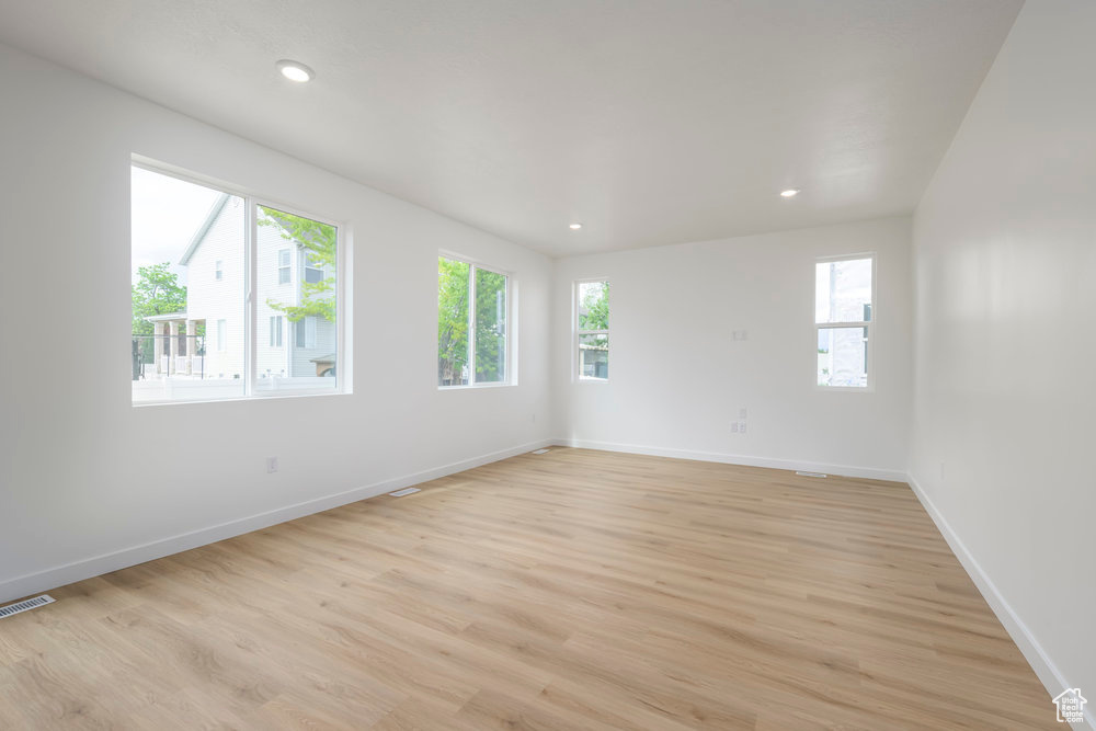 Spare room with plenty of natural light, light wood finished floors, baseboards, and recessed lighting