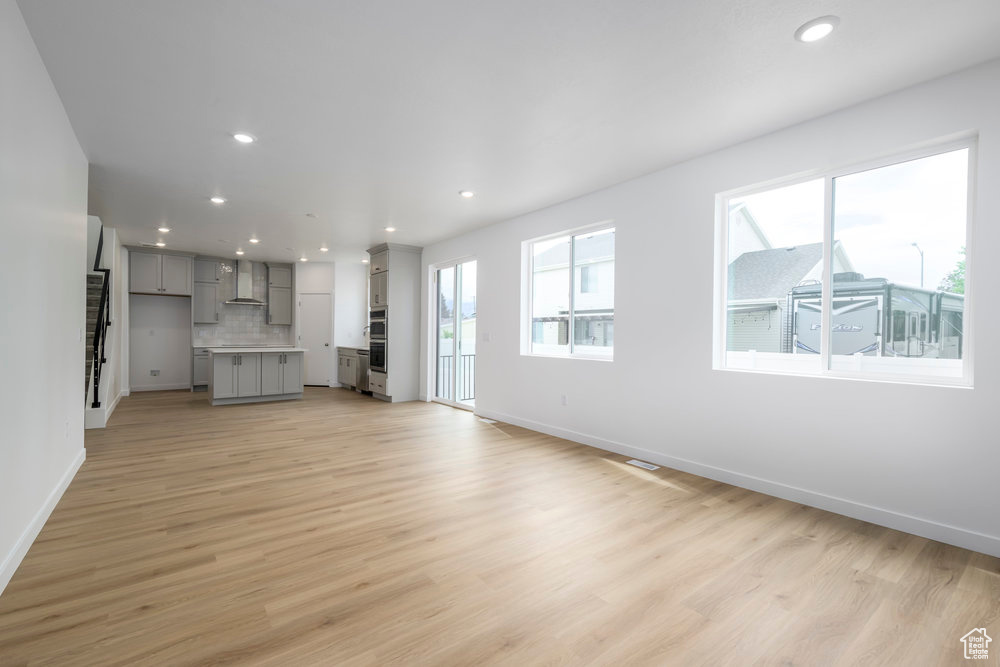 Unfurnished living room with baseboards, recessed lighting, and light wood-style flooring