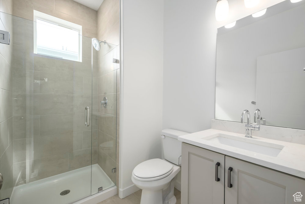 Bathroom with toilet, vanity, a shower stall, and tile patterned flooring