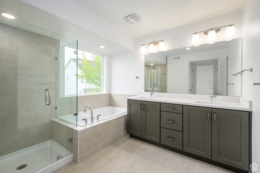 Bathroom featuring double vanity, a bath, a shower stall, and tile patterned flooring