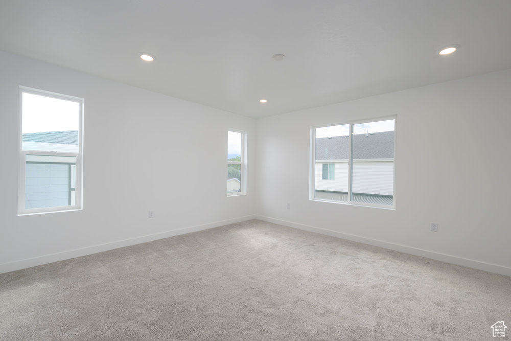 Spare room featuring baseboards, light carpet, and recessed lighting
