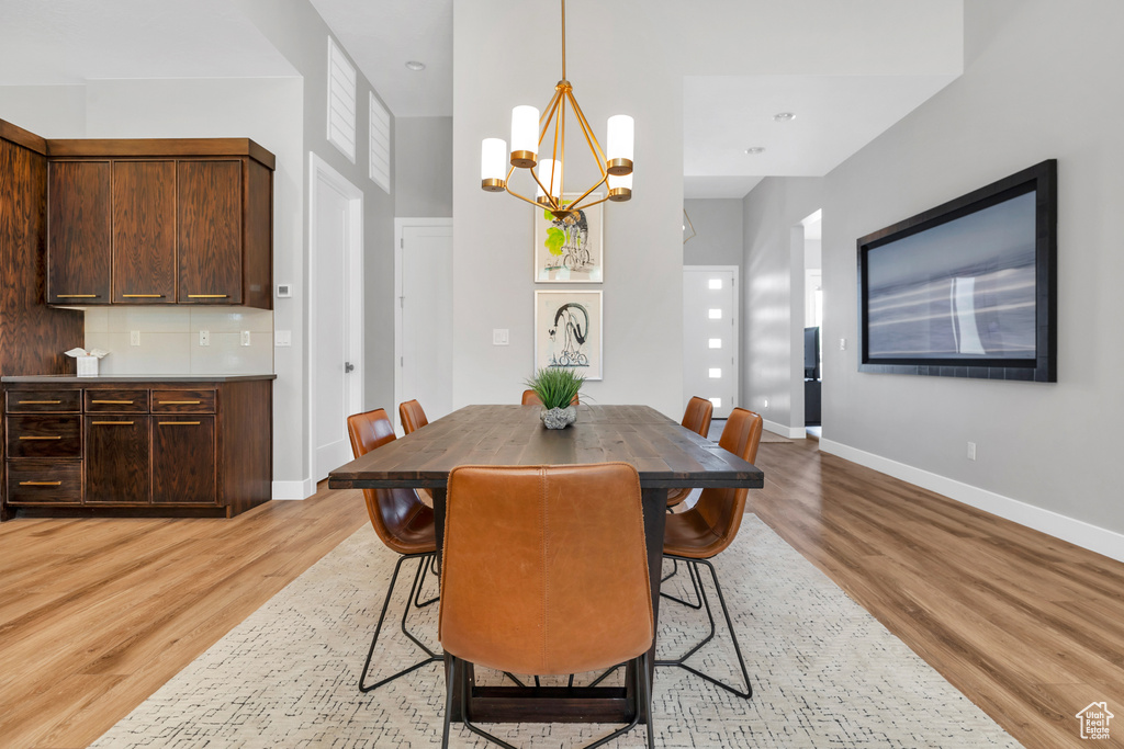 Dining room with baseboards, light wood-type flooring, and an inviting chandelier