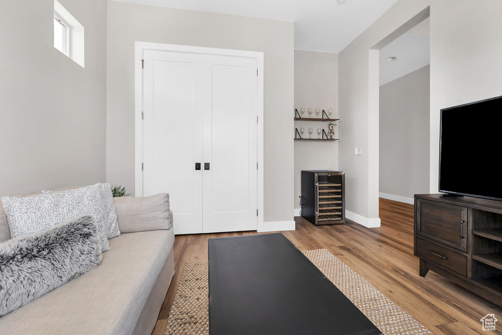 Living room featuring a dry bar, baseboards, wood finished floors, and beverage cooler