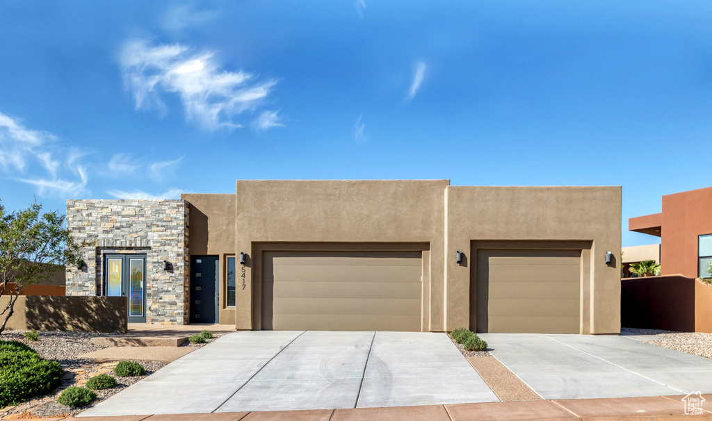 Southwest-style home featuring stucco siding, concrete driveway, an attached garage, and stone siding