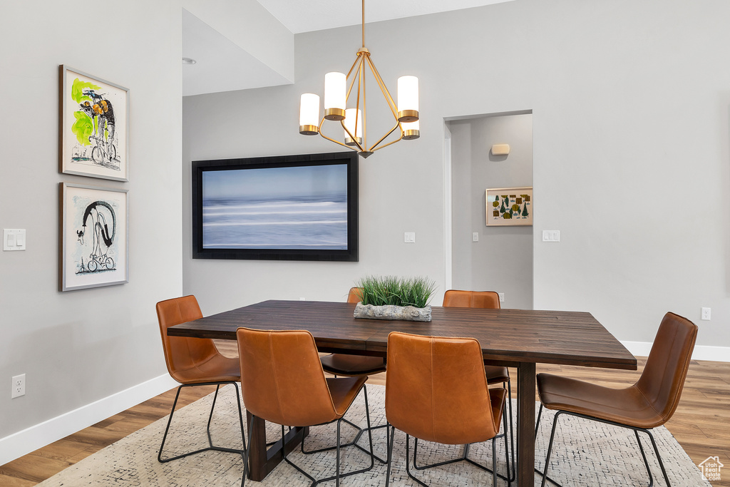 Dining area featuring baseboards, wood finished floors, and a notable chandelier