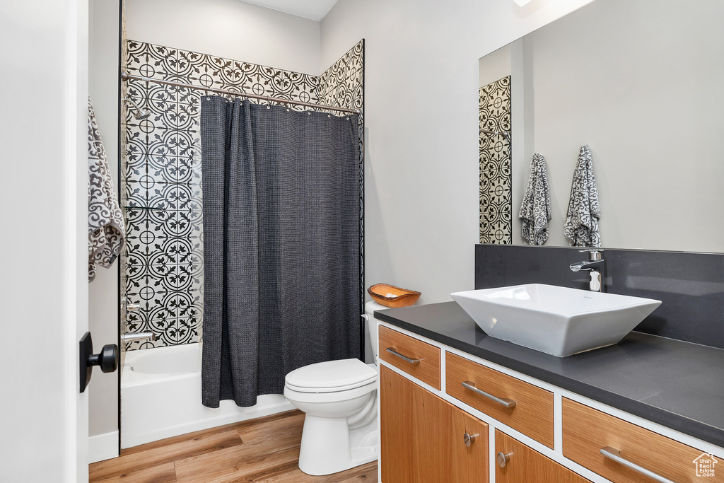 Full bathroom featuring shower / bath combo with shower curtain, toilet, wood finished floors, and vanity