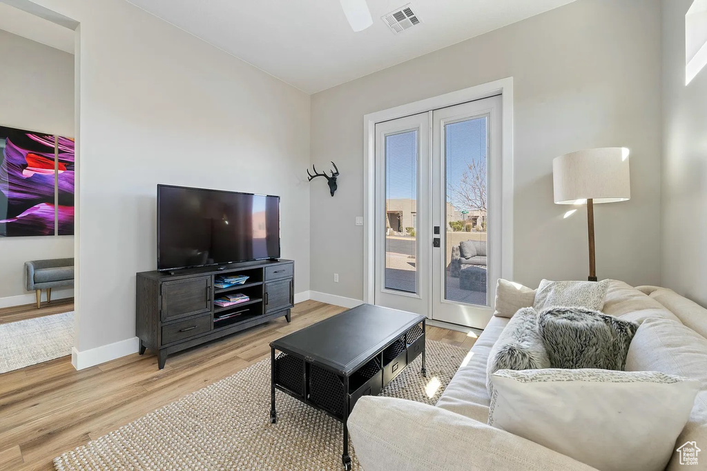 Living area with baseboards, visible vents, a ceiling fan, and light wood finished floors