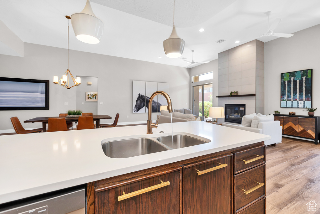Kitchen with hanging light fixtures, light countertops, a fireplace, a sink, and open floor plan