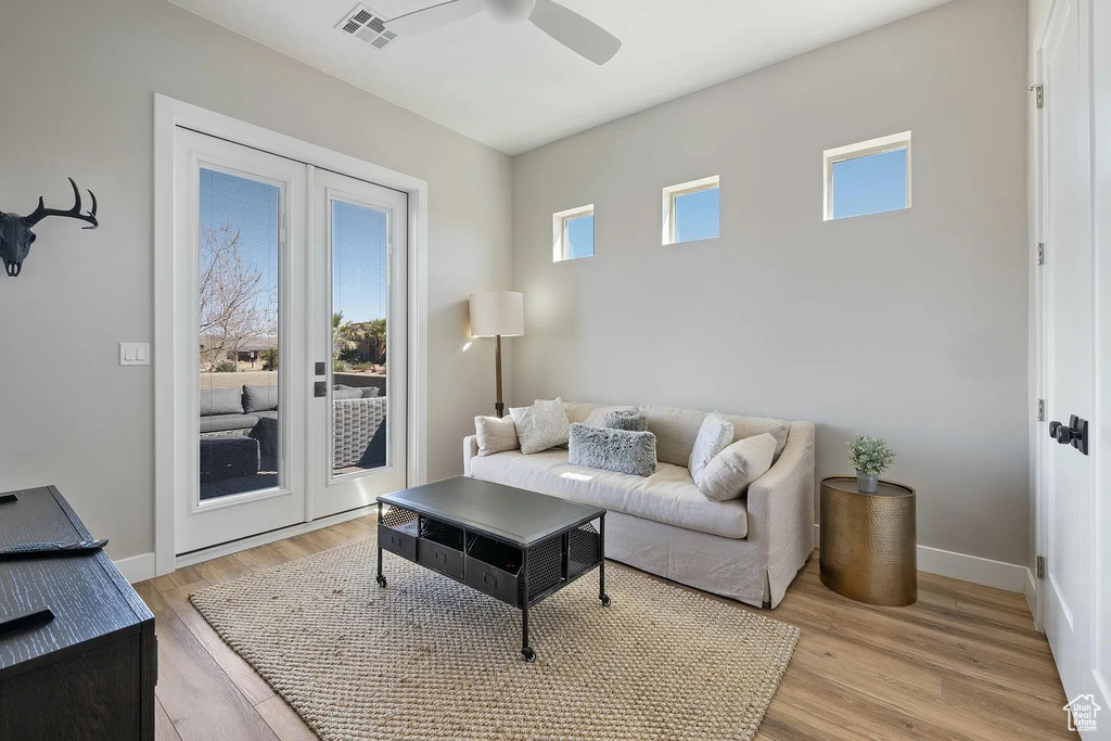 Living area with baseboards, visible vents, a ceiling fan, and light wood-style flooring