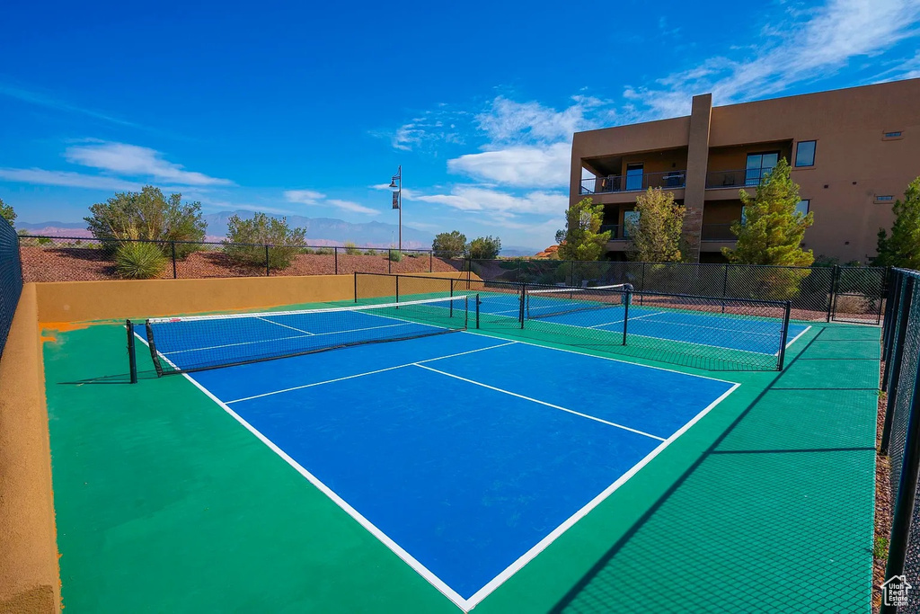 View of tennis court with community basketball court and fence
