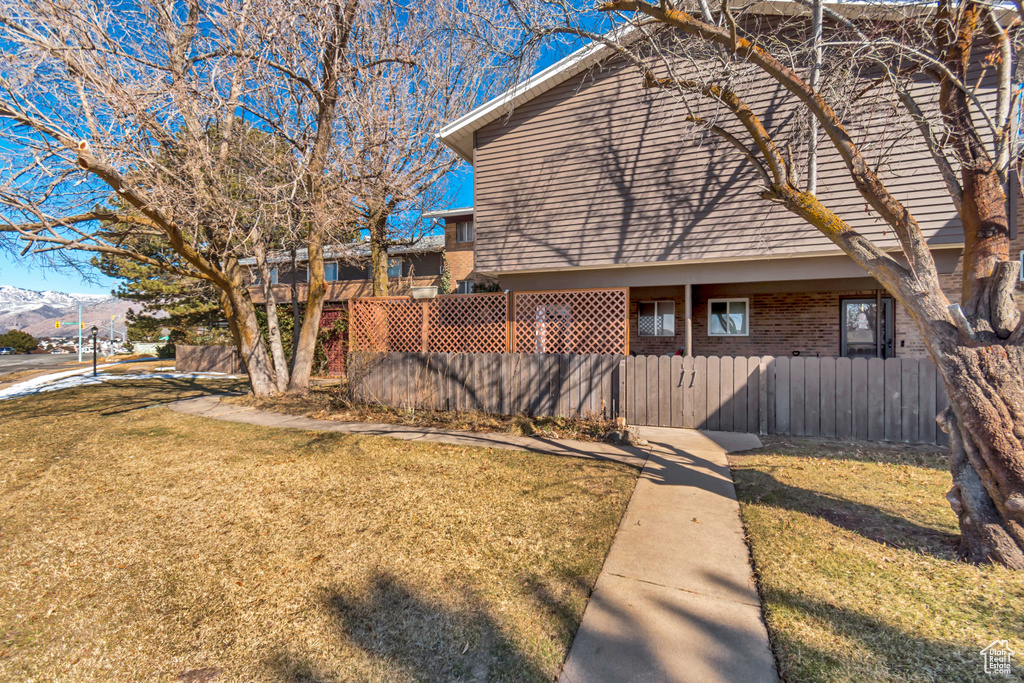 View of side of property with a yard, brick siding, and fence