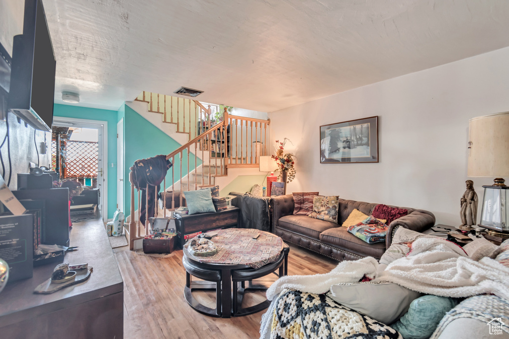 Living area featuring stairs, light wood-type flooring, and visible vents