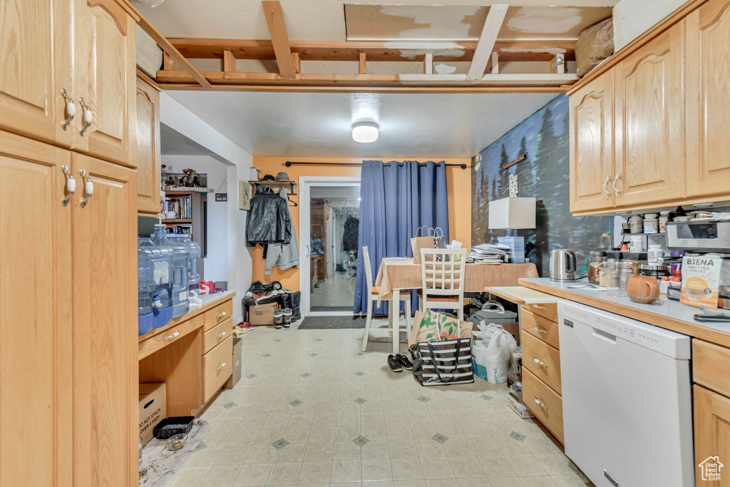 Kitchen with dishwasher, light brown cabinetry, light countertops, and wallpapered walls