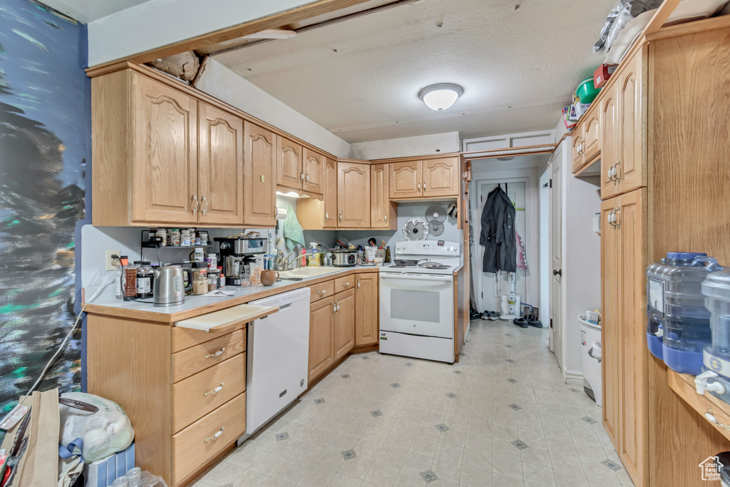 Kitchen with white appliances, light brown cabinets, light countertops, and light floors