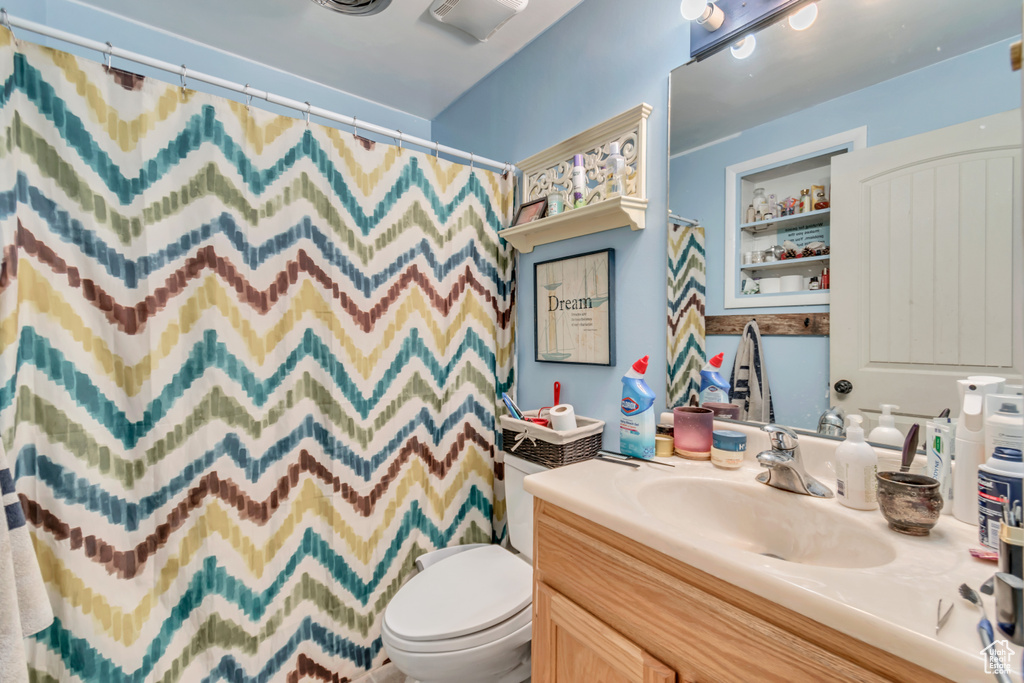 Full bath with visible vents, a shower with shower curtain, vanity, and toilet