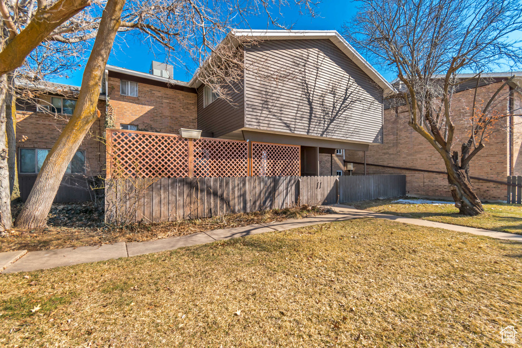 Exterior space with brick siding, a chimney, fence, and a yard