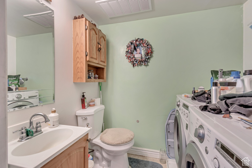 Half bathroom with visible vents, independent washer and dryer, vanity, and toilet