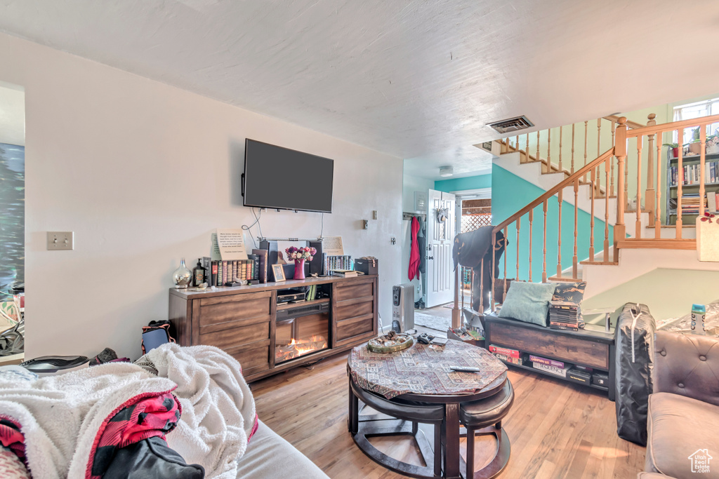 Living room with stairs, visible vents, and wood finished floors