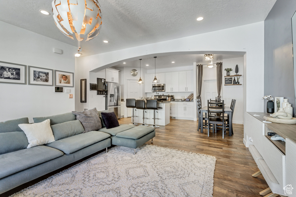 Living room with arched walkways, recessed lighting, a textured ceiling, and wood finished floors