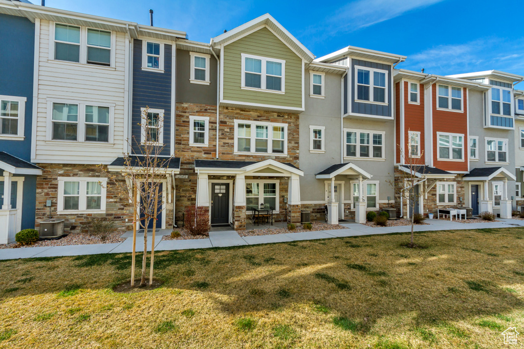 Back of property with stone siding, a residential view, cooling unit, and a lawn