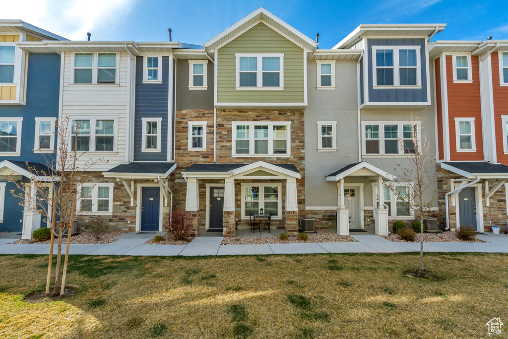 Multi unit property featuring board and batten siding, stone siding, and a front lawn