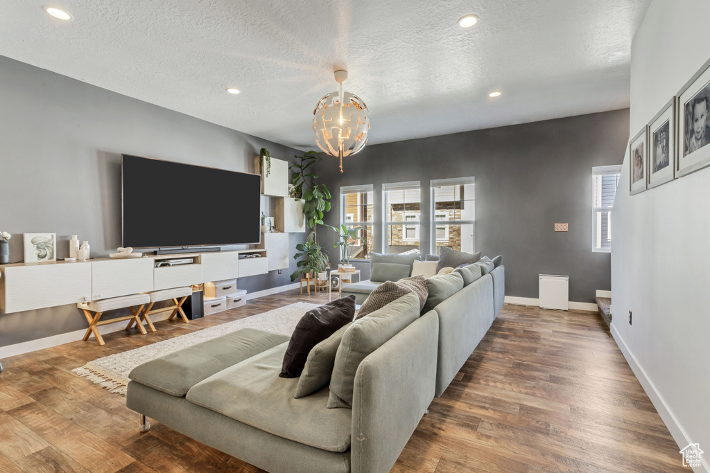 Living room with a textured ceiling, baseboards, and wood finished floors