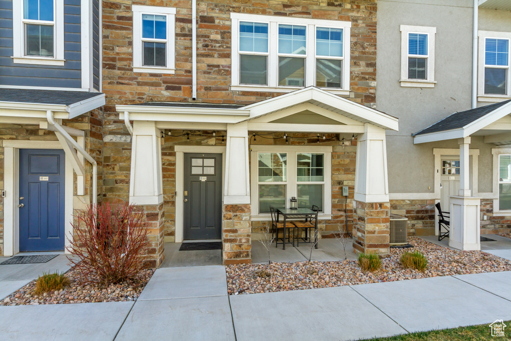 Doorway to property featuring stone siding, french doors, stucco siding, and central air condition unit