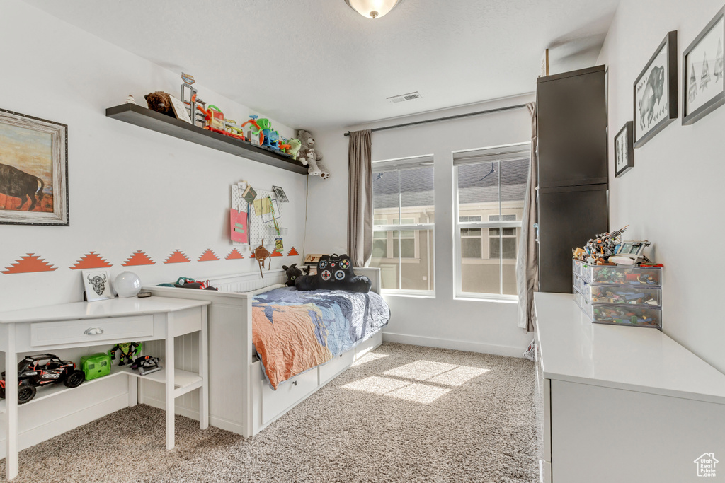 Bedroom with baseboards, visible vents, and light colored carpet