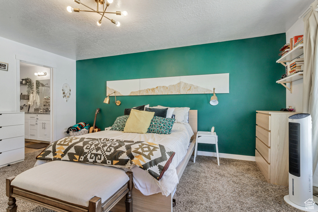 Bedroom with carpet, heating unit, ensuite bathroom, a textured ceiling, and baseboards