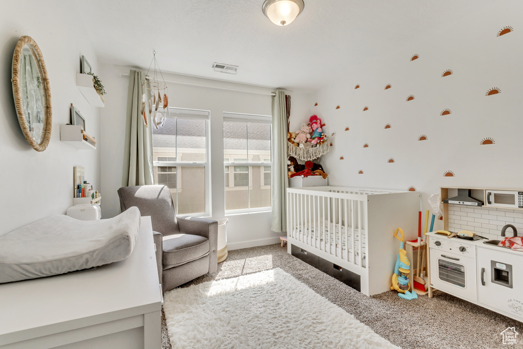 Bedroom featuring carpet floors, a crib, and visible vents