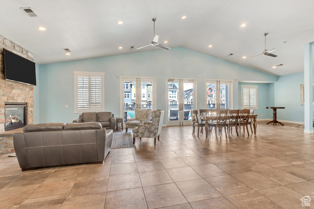 Living room with a healthy amount of sunlight, lofted ceiling, visible vents, and a stone fireplace