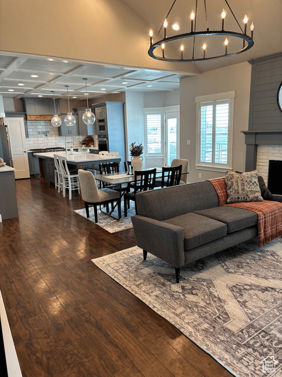 Living area featuring dark wood-type flooring, a chandelier, vaulted ceiling, a fireplace, and recessed lighting