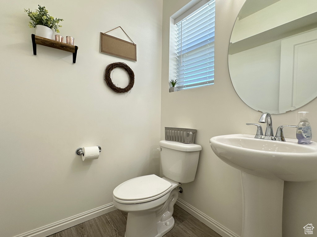 Half bath with a sink, wood finished floors, toilet, and baseboards