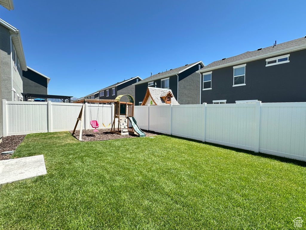 View of yard featuring a playground, a fenced backyard, and a residential view