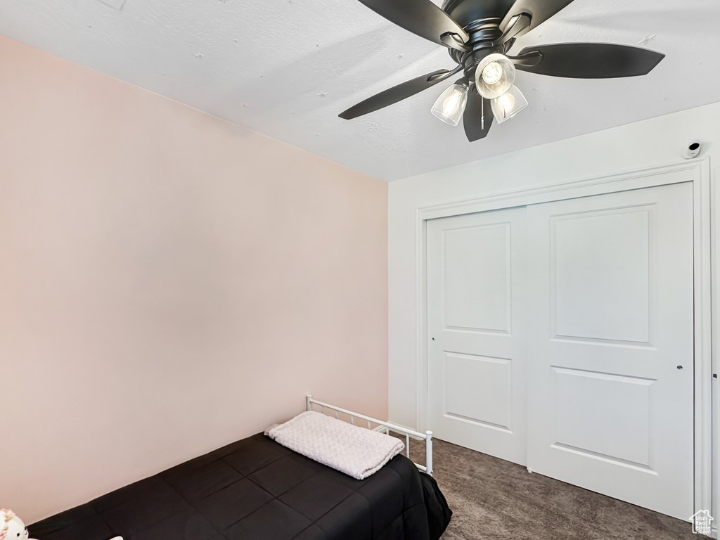 Bedroom featuring ceiling fan, a closet, and dark carpet