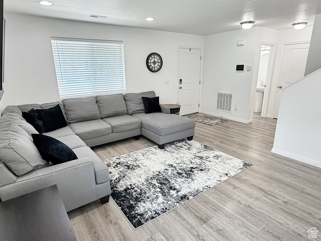 Living area with light wood-style flooring, baseboards, and recessed lighting